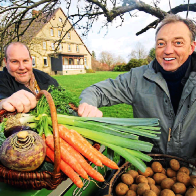 Zwei Männer halten einen Korb mit Gemüse